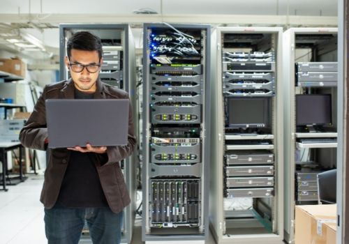 man working on laptop in a server room