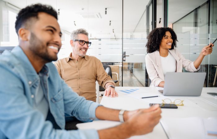 three individuals of an IT team sitting at a conference table smiling