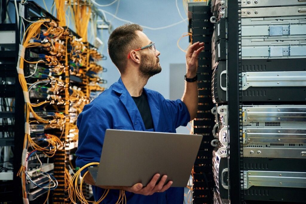 An employee checking cables in a server room